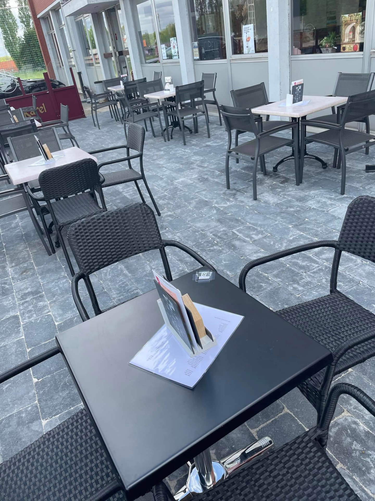 Het terras vooraan met zwarte tafels en stoelen